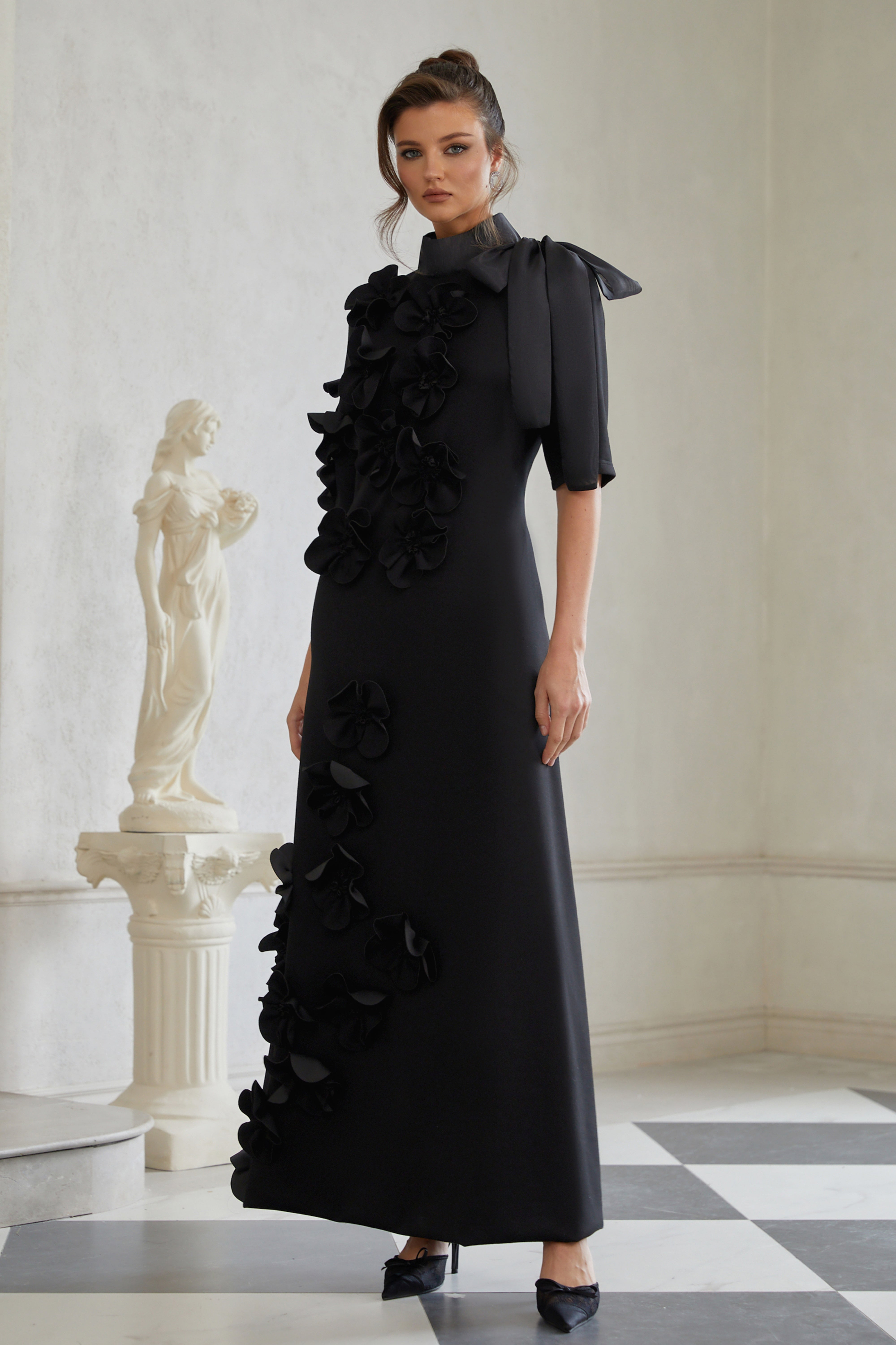 Isidora Schwarzes Maxikleid mit Schleife und Blumenapplikation